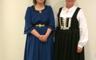 Stúlka í kyrtli, skátar standa sitthvoru megin við hana og stiðja víð Íslenska fánann.
