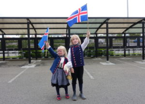 Annríki - Þjóðbúningar og skart. Stúlka í 19. aldar upphlut og drengur í herrabúning. Börnin halda á íslensku fánunum.
